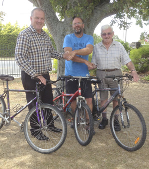 Principal Craig Nelson accepting 3 refurbished bikes from Richard Tannant, Shed Manager with sponsor Stuart Edward of Green Jersey Cycle Tours.