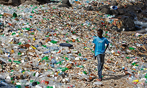 a boy from Senegal walking along a polluted beach strewn with predominantly plastic bottles in the village of Ngor, Dakar, Senegal. Photograph: Nic Bothma/EPA